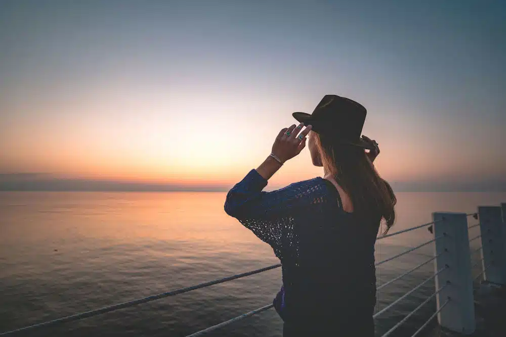 a-woman-holding-her-hat-admiring-the-sunset-on-the-beach