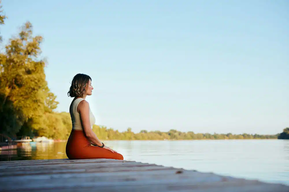 a-woman-sitting-on-a-pier-meditating