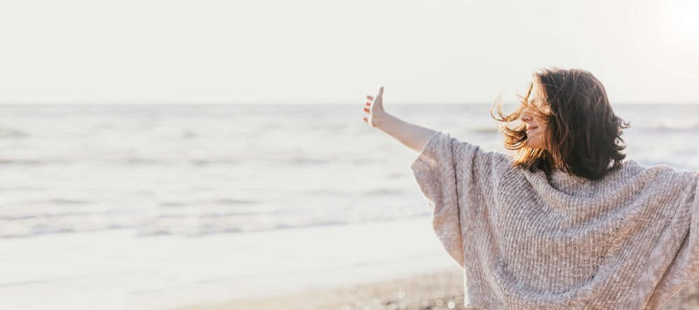 a-woman-with-arms-wide-on-a-beach