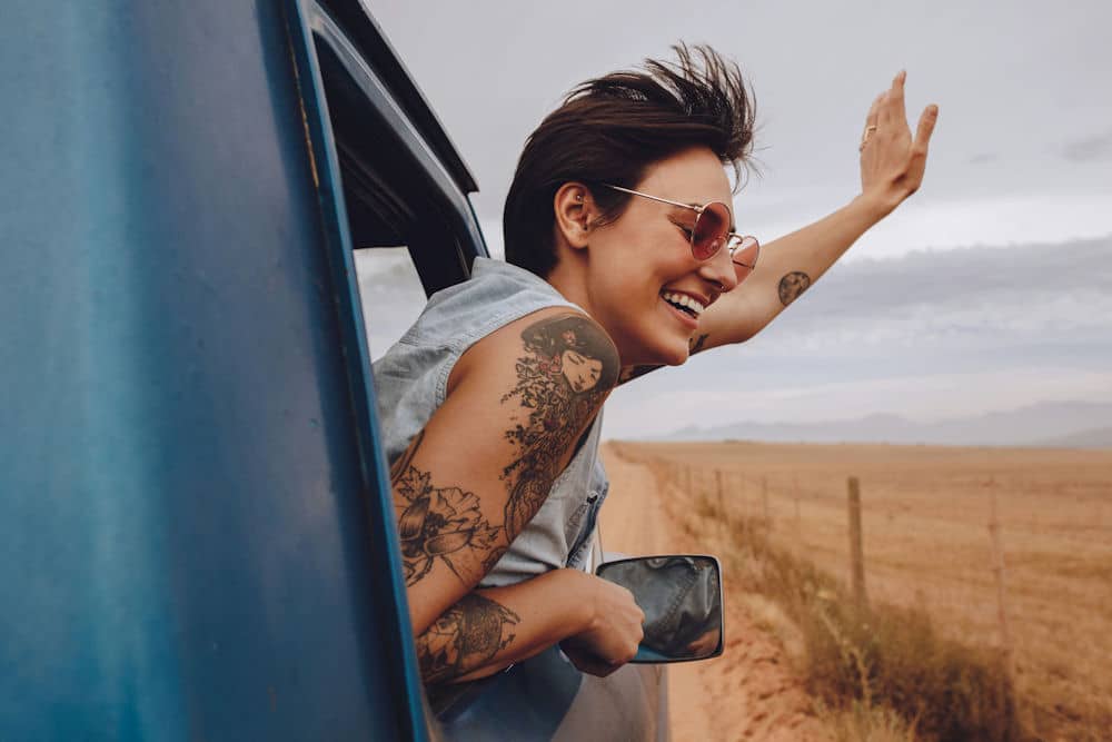 a-woman-smiling-happy-waving-outside-of-the-car