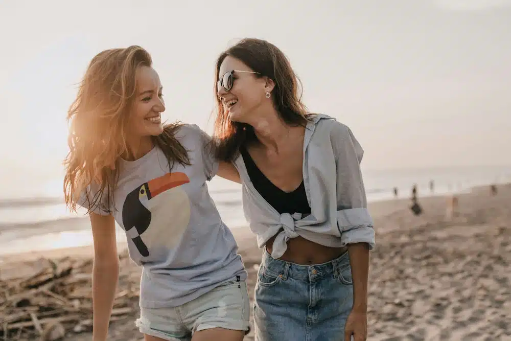 two-girls-smiling-looking-at-each-other-on-the-beach