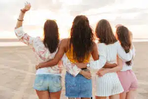 a-group-of-girls-holding-each-other-backs-turned-on-the-beach