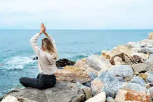 a-woman-doing-yoga-on-the-beach-sitting-on-rocks