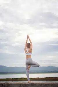 a-woman-practicing-yoga-outside-near-the-water