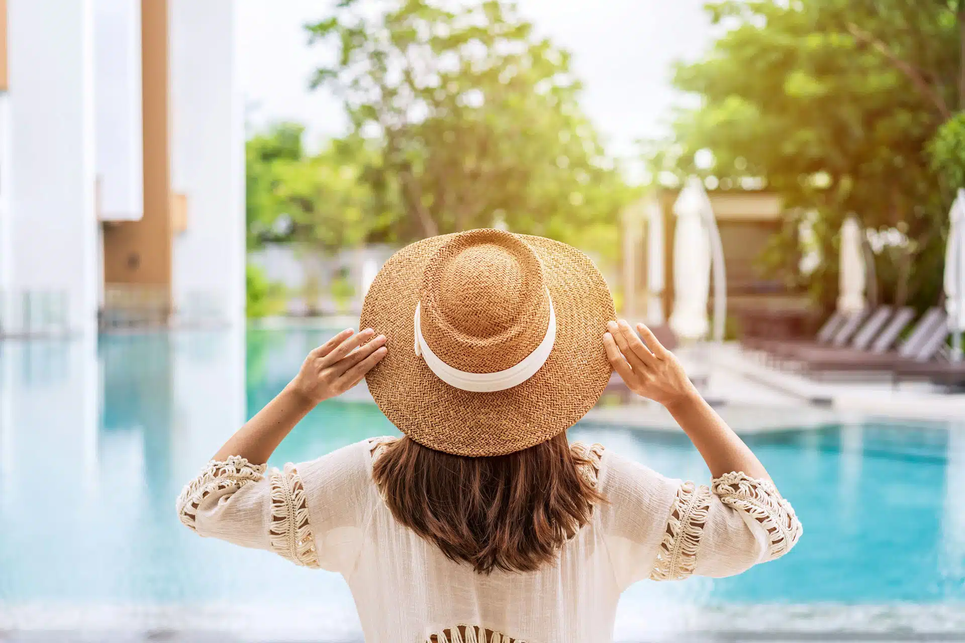 a-woman-holding-her-hat-staring-at-her-pool