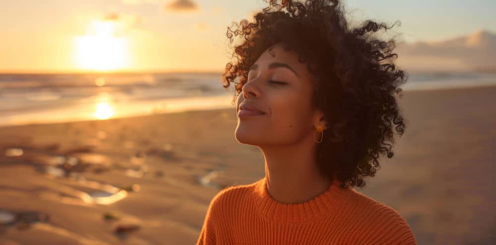 a-woman-meditating-on-the-beach-during-the-sunset