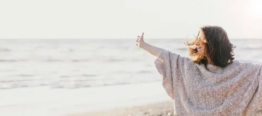 a-woman-smiling-with-hands-lifted-embracing-recovery