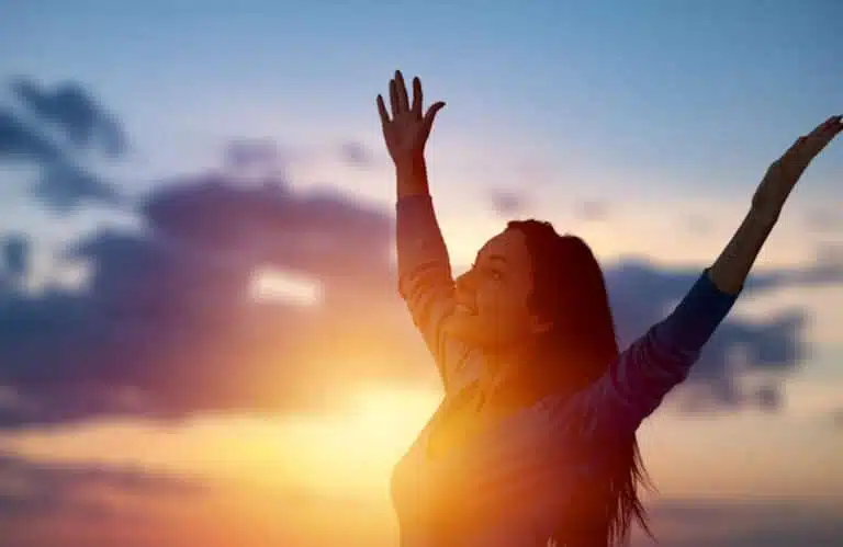 a-woman-embracing-freedom-with-her-hands-up