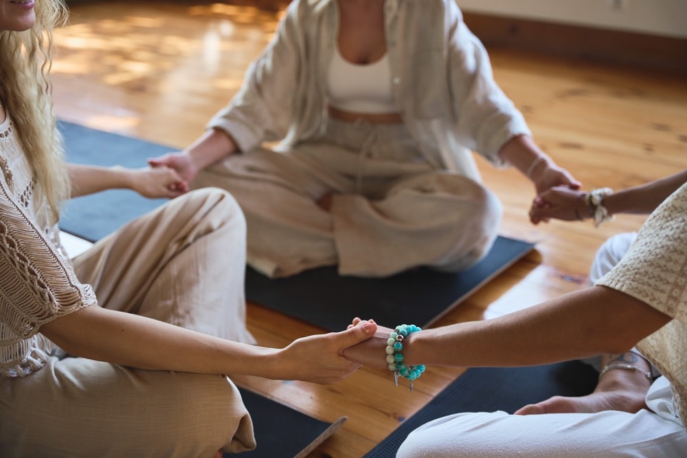 group of women holding hands practicing yoga