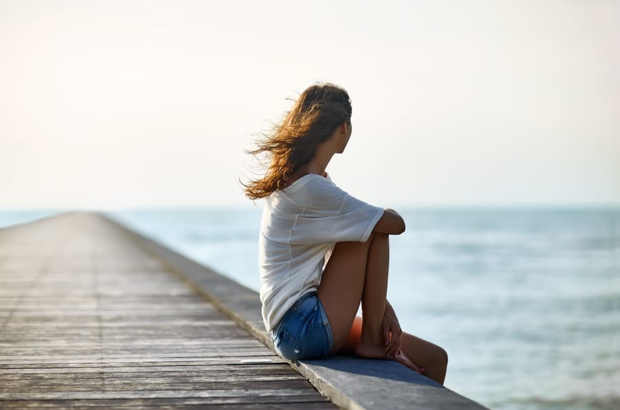 a-woman-looking-away-sitting-on-a-pier