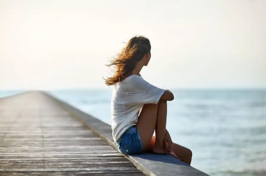 a woman looking away sitting on a pier