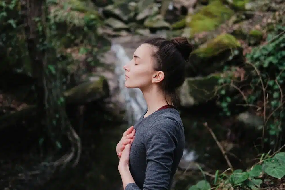 A Woman Holding Her Chest Meditating in Nature