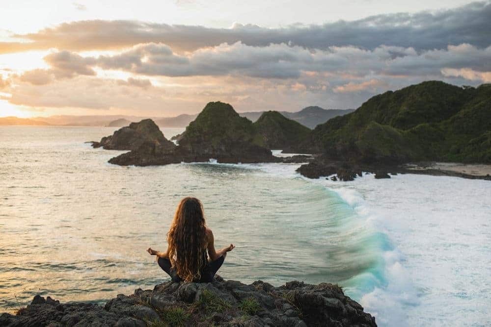 a woman sitting on rocks at the beach