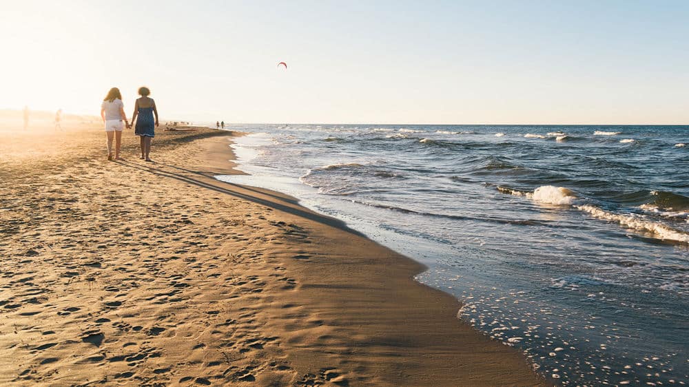 women-holding-hands-walking-on-the-beach