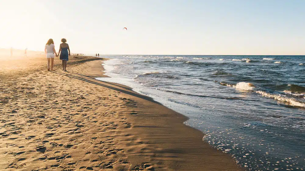 women-holding-hands-walking-on-the-beach