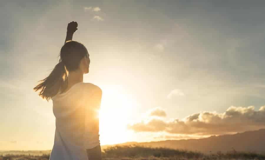 a woman with her hand raised outside in nature