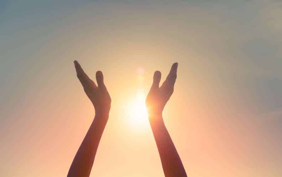 a pair of hands pointing to the sun